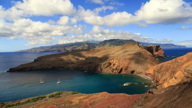 Blick auf die zerklüftete Küste von Ponta de São Lourenço, Madeira, mit zwei Segelbooten in der Bucht.