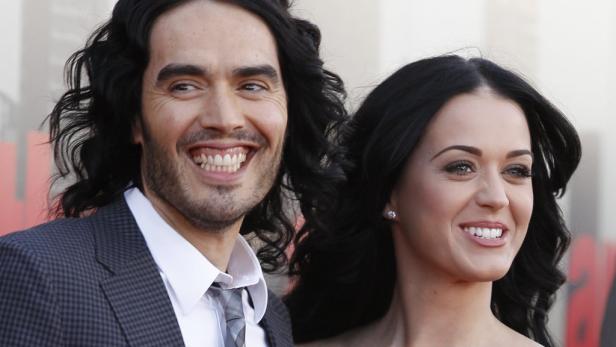 Russell Brand und Katy Perry lächeln auf einem roten Teppich.