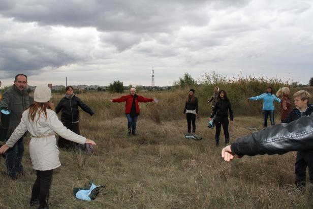 Eine Gruppe von Menschen steht mit ausgestreckten Armen auf einem Feld.