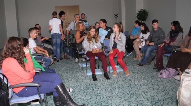 Eine Gruppe von Menschen sitzt in einem Raum und hört aufmerksam zu.