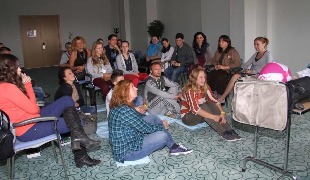 Eine Gruppe von Menschen sitzt in einem Raum und schaut in eine Richtung.