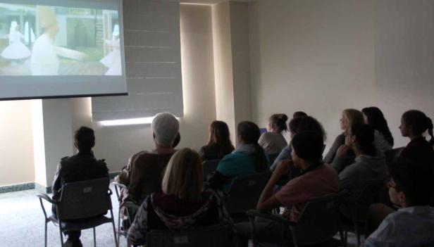 Eine Gruppe von Menschen schaut sich eine Projektion von Derwischen an.