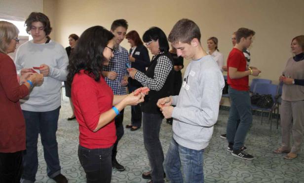 Eine Gruppe von Menschen steht in einem Raum und tauscht kleine Zettel aus.