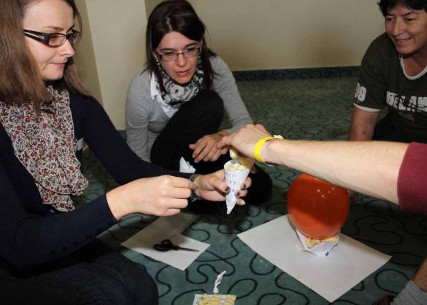 Eine Gruppe von Personen sitzt auf dem Boden und bastelt an einem Projekt mit einem Ballon und Papier.
