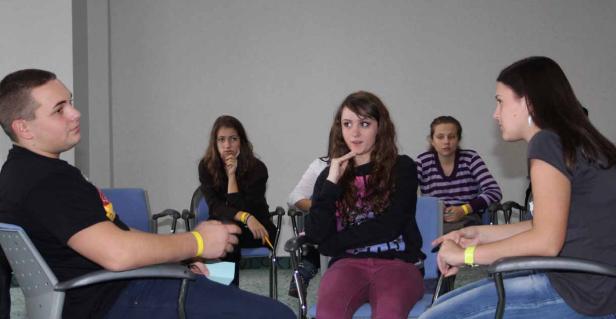 Eine Gruppe junger Leute sitzt in einem Raum und diskutiert.