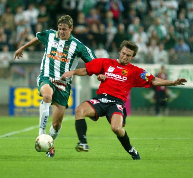 Zwei Fußballspieler kämpfen um den Ball auf dem Spielfeld.