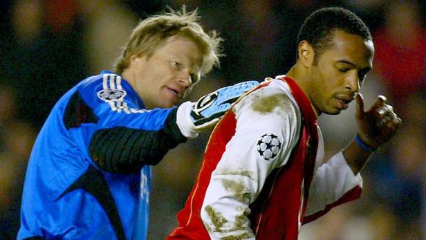 Oliver Kahn berührt den Rücken von Thierry Henry während eines Fußballspiels.