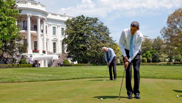 Barack Obama spielt mit einem anderen Mann Golf vor dem Weißen Haus.
