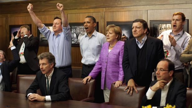 Eine Gruppe von Politikern, darunter Obama und Merkel, jubeln und applaudieren.