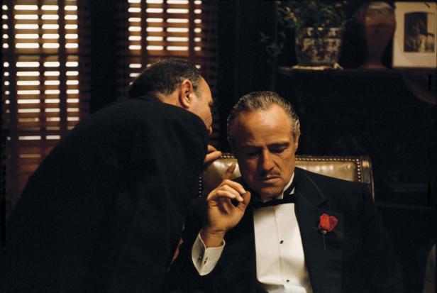 Marlon Brando als Don Vito Corleone im Film „Der Pate“, dem ein Mann etwas ins Ohr flüstert.