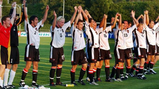 Eine Fußballmannschaft jubelt mit erhobenen Armen auf dem Rasen.