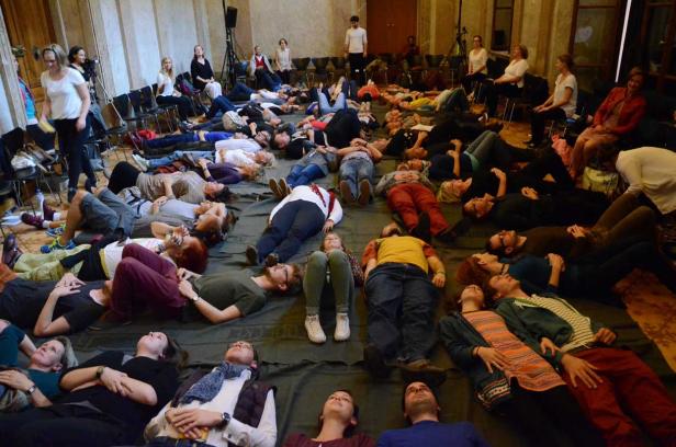 Eine Gruppe von Menschen liegt auf dem Boden und schaut nach oben.