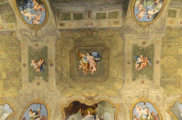 Detailansicht der bemalten Decke eines historischen Gebäudes mit mythologischen Szenen.