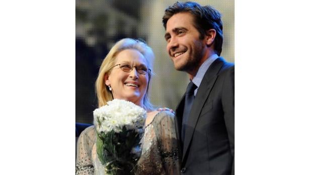 Meryl Streep mit einem Blumenstrauß und Jake Gyllenhaal lächeln.