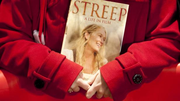Eine Person im roten Blazer hält ein Buch über Meryl Streep in den Händen.