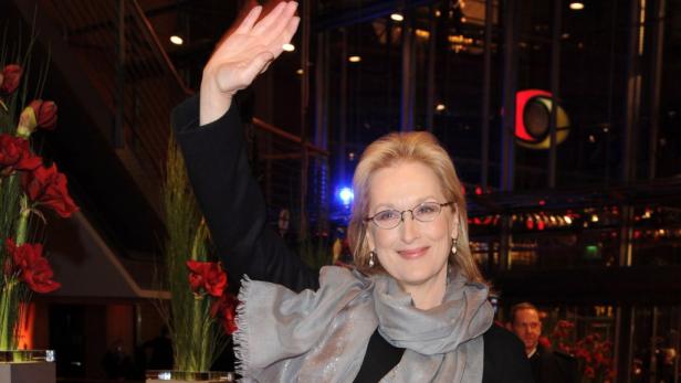 Meryl Streep winkt mit einem grauen Schal um den Hals.