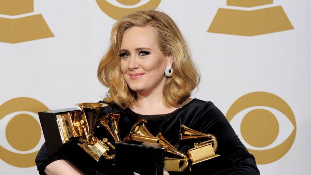 Adele hält mehrere goldene Grammy Awards in ihren Armen.