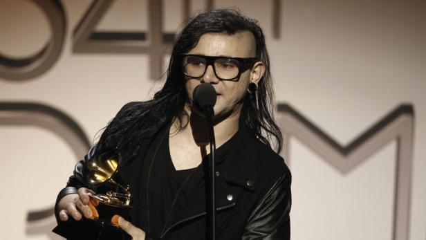 Skrillex hält eine Grammy-Trophäe in der Hand und spricht in ein Mikrofon.
