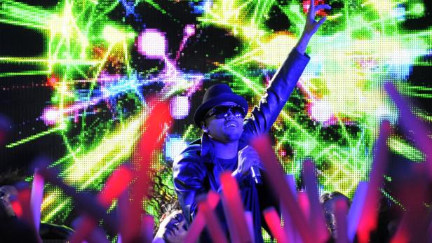 Chris Brown tritt vor einer jubelnden Menge und einer bunten LED-Wand auf.