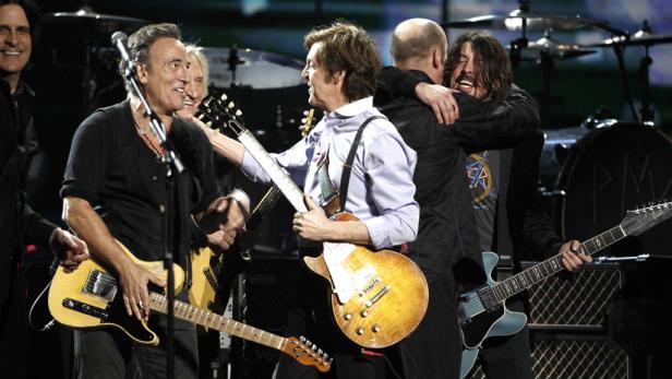 Bruce Springsteen, Paul McCartney und Dave Grohl umarmen sich auf der Bühne.
