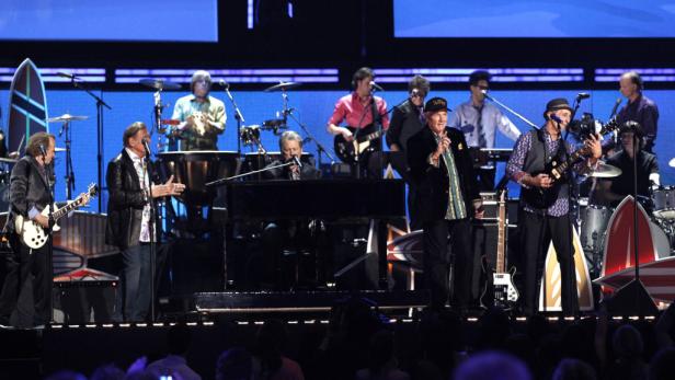Die Beach Boys treten auf einer Bühne mit Surfbrettern als Dekoration auf.