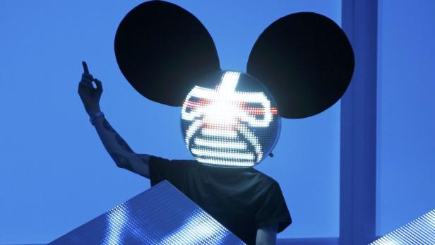 Ein DJ mit einer leuchtenden, mausohrähnlichen Maske legt Musik auf.