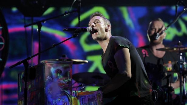 Chris Martin von Coldplay singt am Klavier während eines Konzerts.