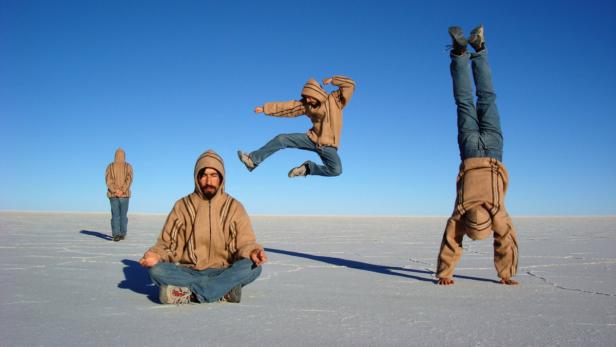 Ein Mann in verschiedenen Posen auf einer weiten, weißen Ebene unter blauem Himmel.