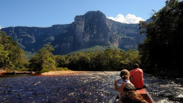 Eine Bootsfahrt auf einem Fluss mit Blick auf einen Tafelberg und üppige Vegetation.