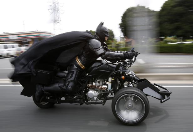 Batman fährt ein ungewöhnliches, dreirädriges Motorrad auf einer Straße.