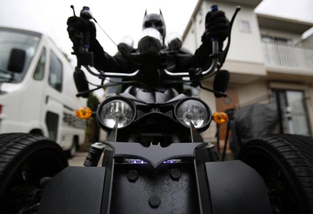 Eine Person im Batman-Kostüm auf einem Motorrad mit Batman-Logo vorne.