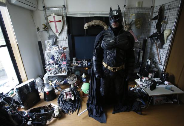 Eine Person in einem Batman-Kostüm steht in einem Raum voller Sammlerstücke.