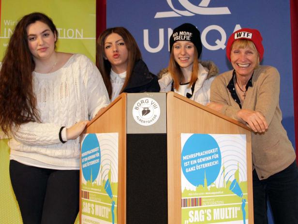 Vier Frauen stehen an einem Rednerpult mit dem Slogan „Sag’s Multi!“.