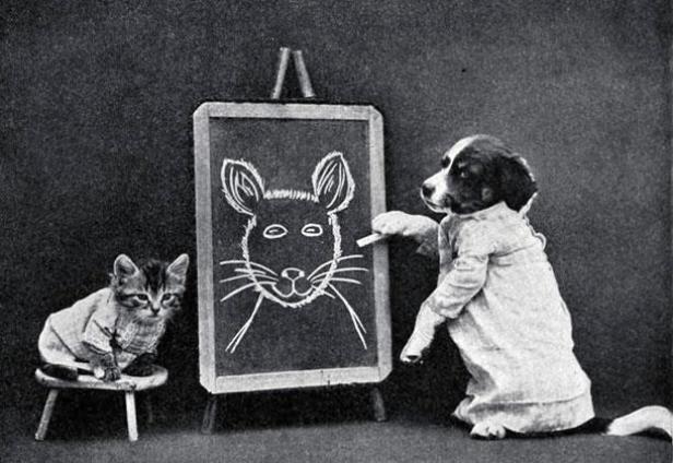 Ein Hund zeichnet ein Katzenporträt auf eine Tafel, während eine Katze zusieht.