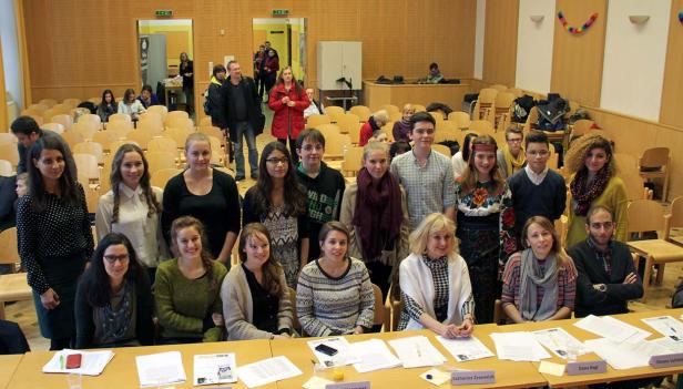 Eine Gruppe von Menschen posiert in einem Raum mit Tischen und Stühlen für ein Foto.