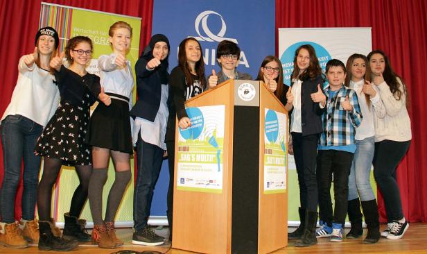 Eine Gruppe Jugendlicher steht auf einer Bühne und gibt die Daumen hoch.