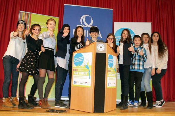 Eine Gruppe Jugendlicher steht auf einer Bühne und zeigt die Daumen nach oben.