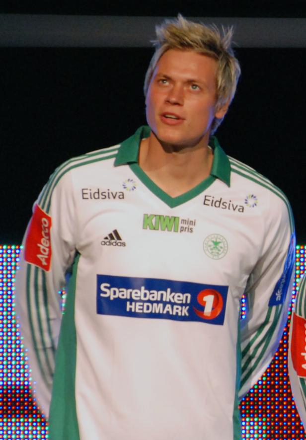 Ein Mann in einem Fußballtrikot mit verschiedenen Sponsorenaufdrucken.