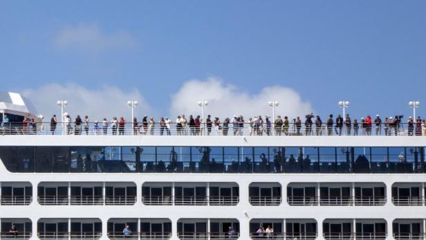Viele Menschen stehen auf dem Deck eines Kreuzfahrtschiffes.