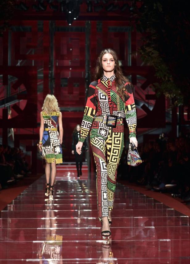 Eine Frau in einem farbenfrohen Hosenanzug auf einem Laufsteg.