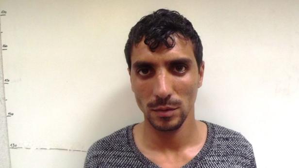 Porträt eines Mannes vor einer weißen Wand mit Größenmarkierungen.