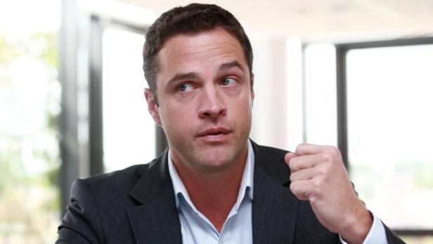 Ein Mann im Anzug blickt nachdenklich zur Seite und ballt die Faust.