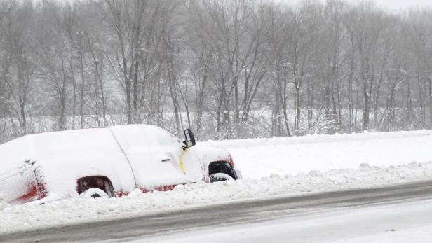 Ein roter Lieferwagen ist im Schnee stecken geblieben.