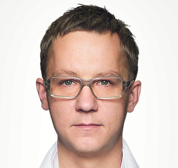 Ein Mann mit hellbraunen Haaren und einer transparenten Brille blickt in die Kamera.