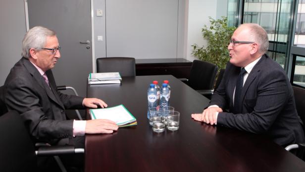 Zwei Männer in Anzügen sitzen an einem Konferenztisch und unterhalten sich.