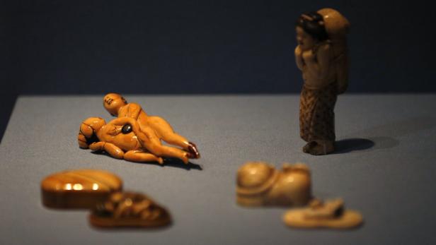 Eine Sammlung japanischer Netsuke-Figuren auf einer grauen Oberfläche.