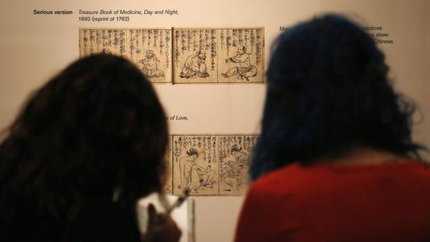 Zwei Personen betrachten eine Ausstellung von alten chinesischen medizinischen Texten.