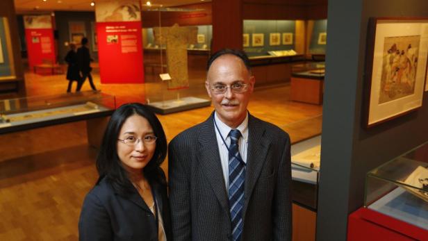 Zwei Personen posieren vor Ausstellungsstücken in einem Museum.