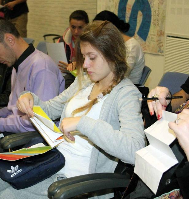 Eine junge Frau sitzt und betrachtet farbiges Papier.