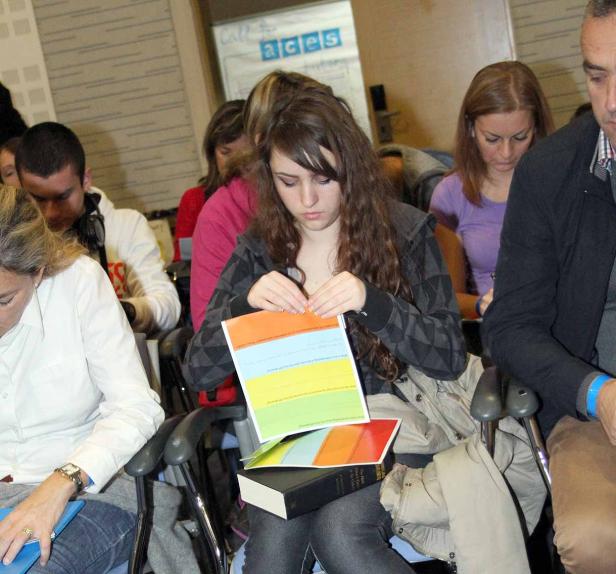 Eine junge Frau sitzt in einem Raum und betrachtet ein farbiges Dokument.